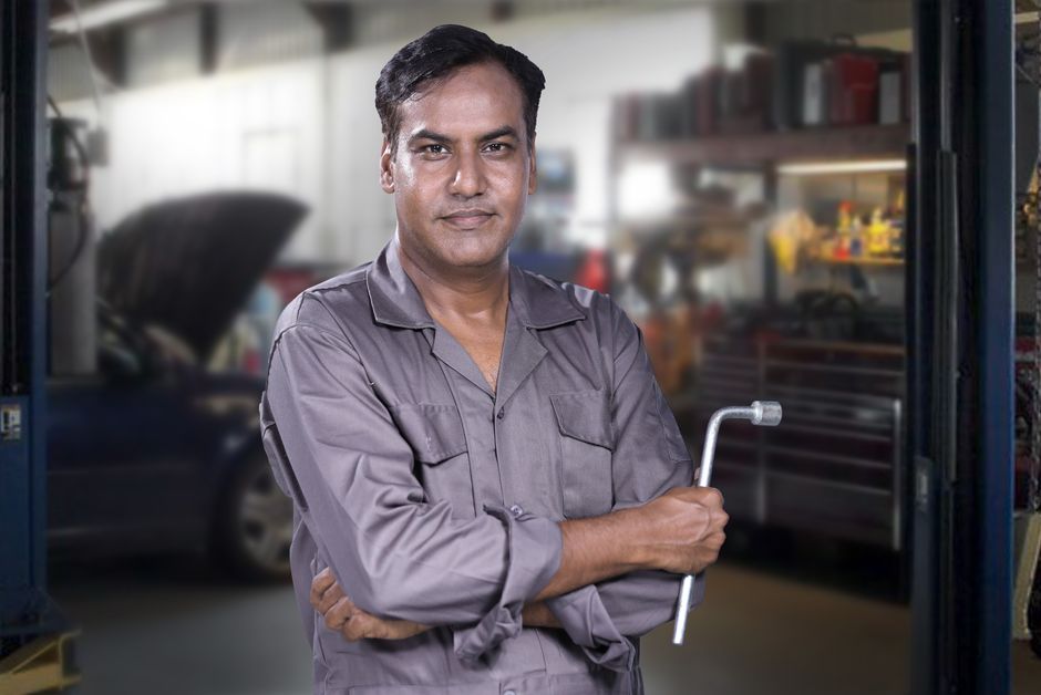 Friendly auto mechanic inspecting a vehicle in the service bay